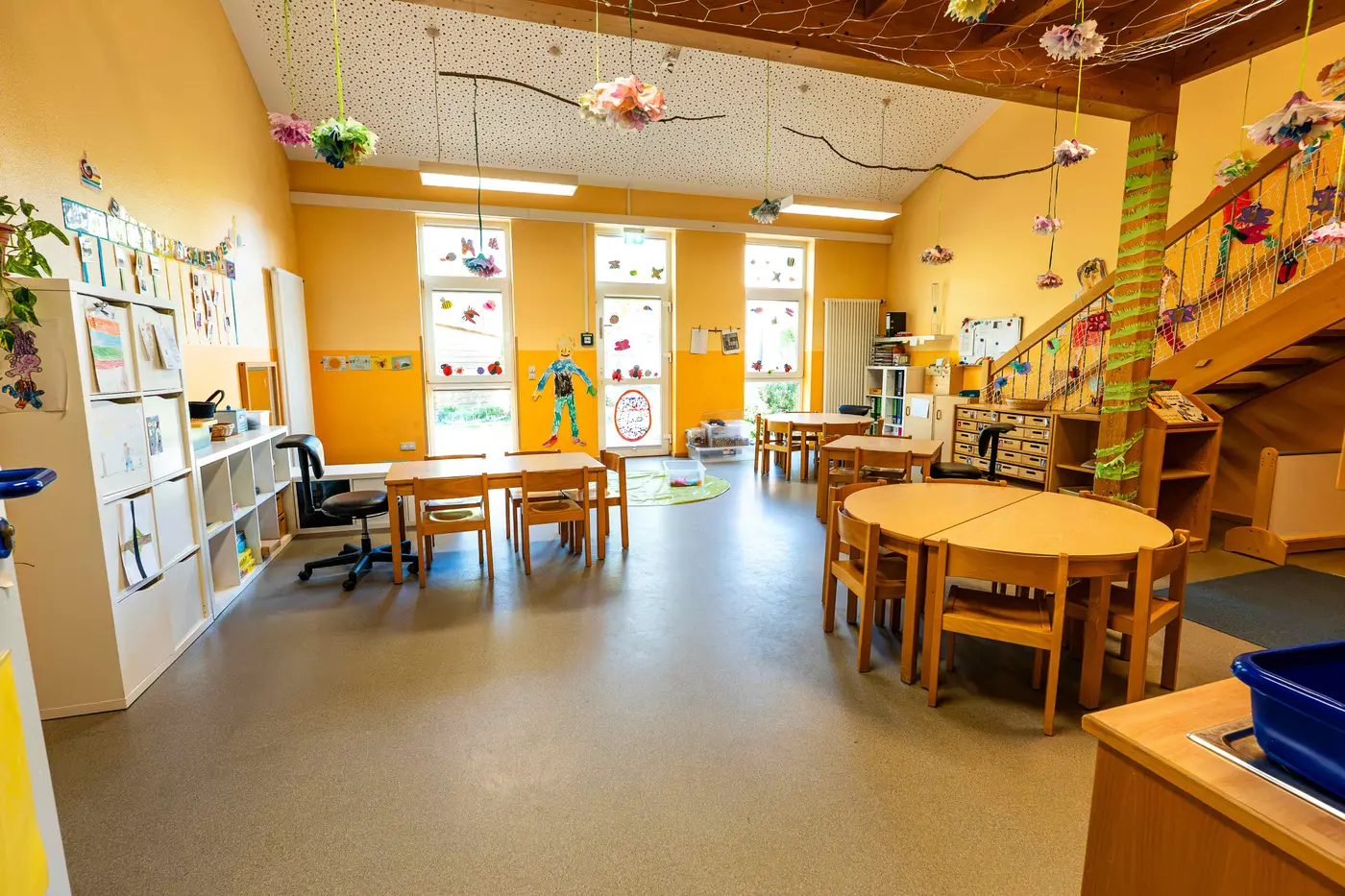Heller Gruppenraum der Regelgruppen mit Kindertischen und Hängedekoration in der Kindertagesstätte Schweich