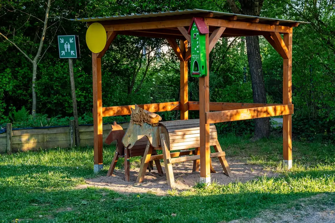 Hölzernes Spielpferd unter einer Pergola im Garten der Kita Schweich