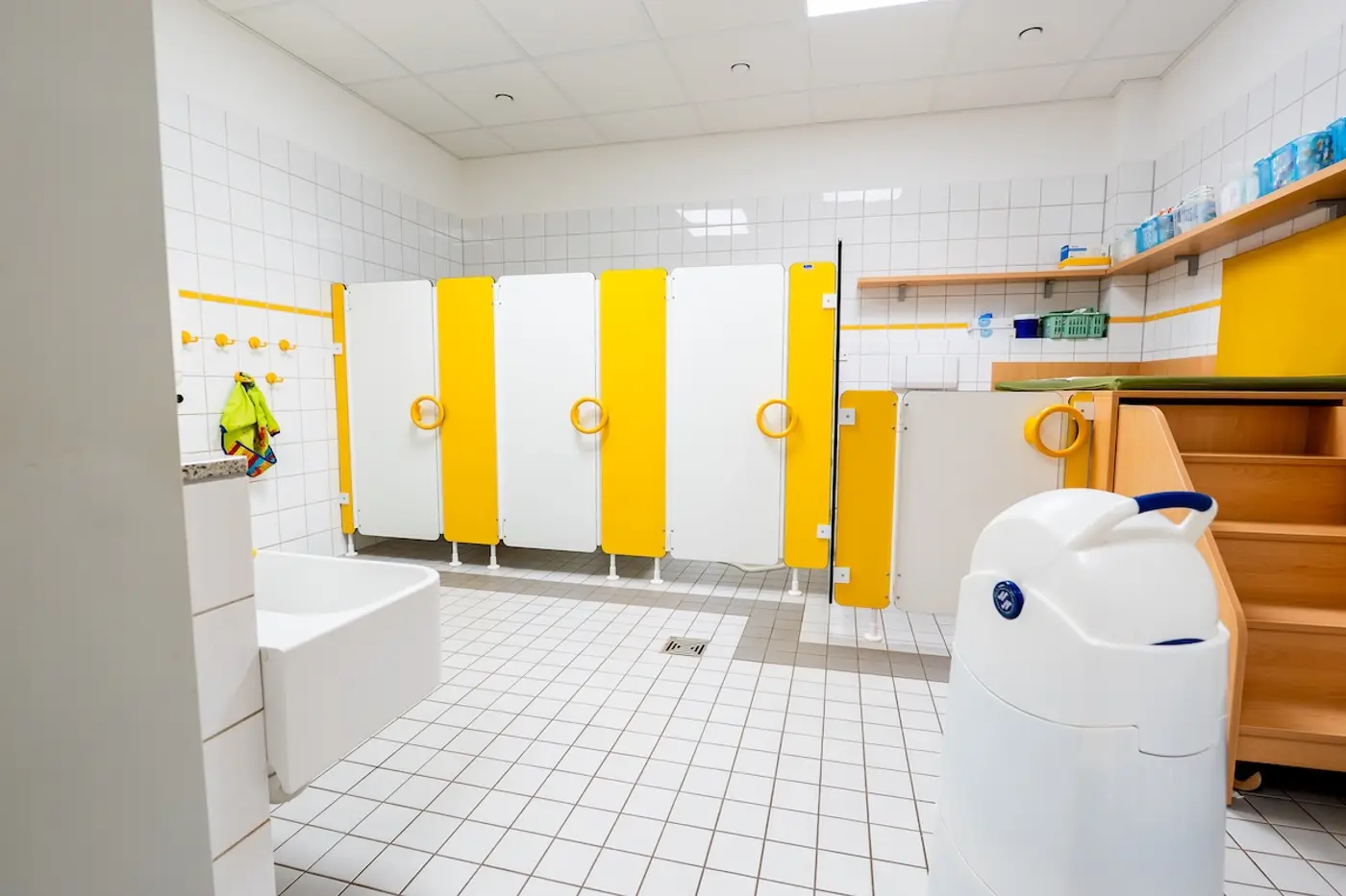 Kindertoiletten der Kita Schweich mit gelb-weißen Trennwänden auf weißen Fliesen